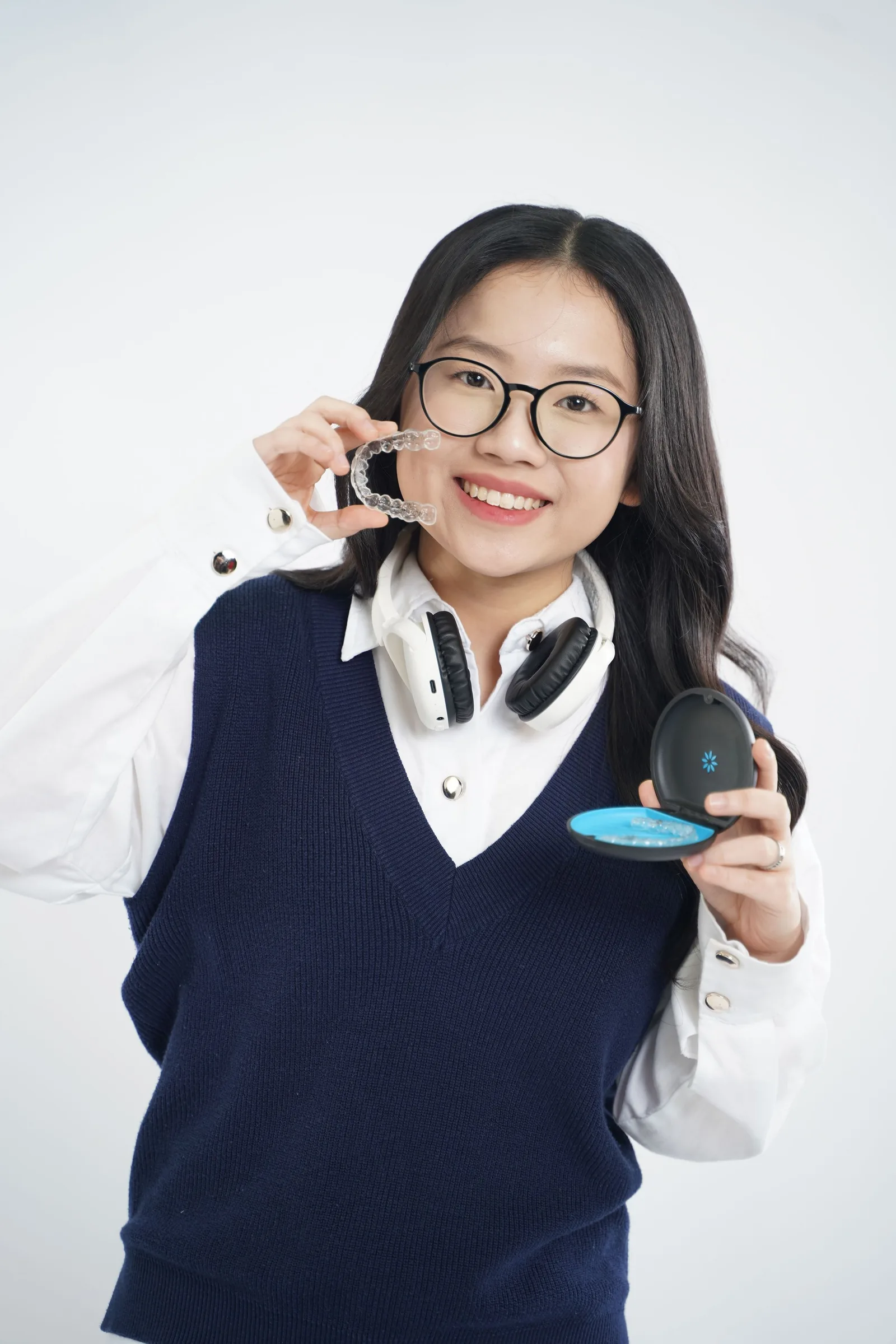 Person smiling while holding a clear aligner