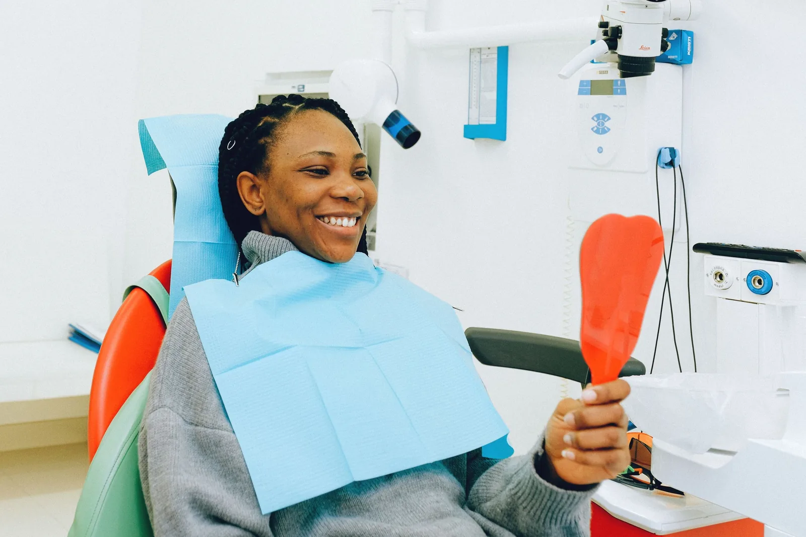 Patient in a dental chair smiling into a hand mirror