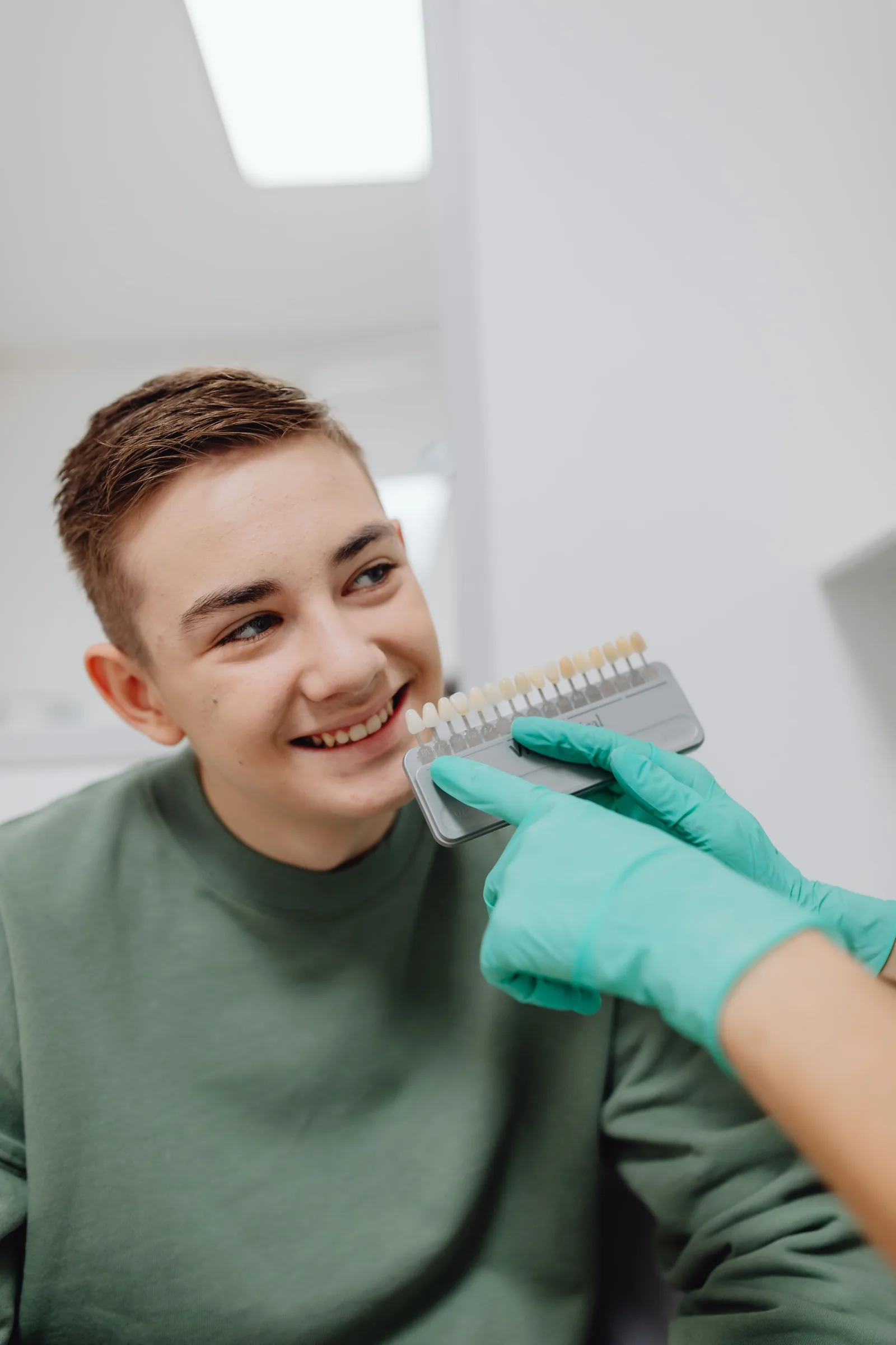 Dentist holding a shade guide next to a young patient